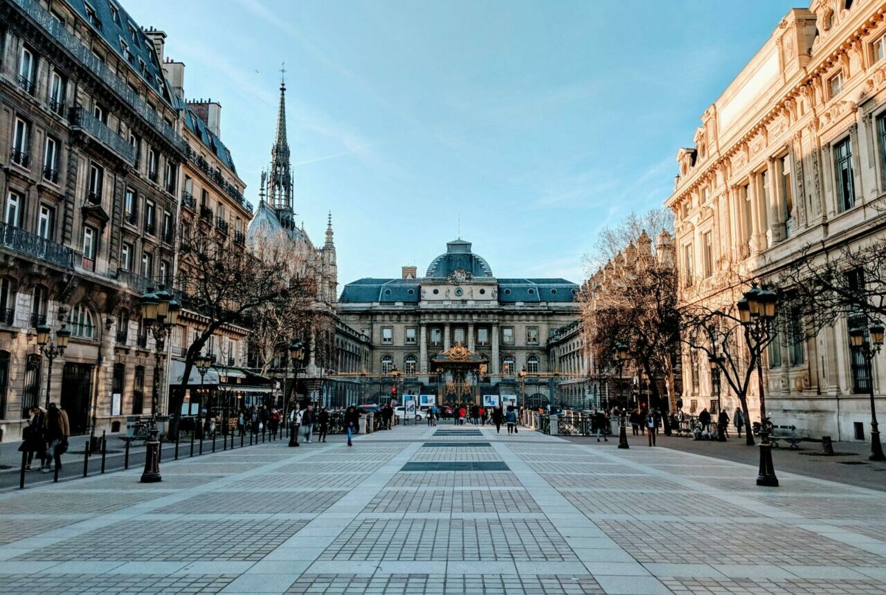 A vibrant street view of Paris featuring the Palace of Justice with a clear blue sky.
